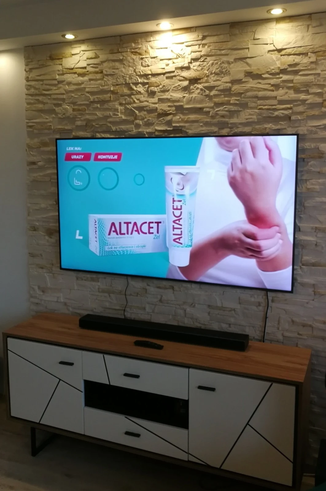 Telewizor i soundbar zamontowane na ścianie z kamienia