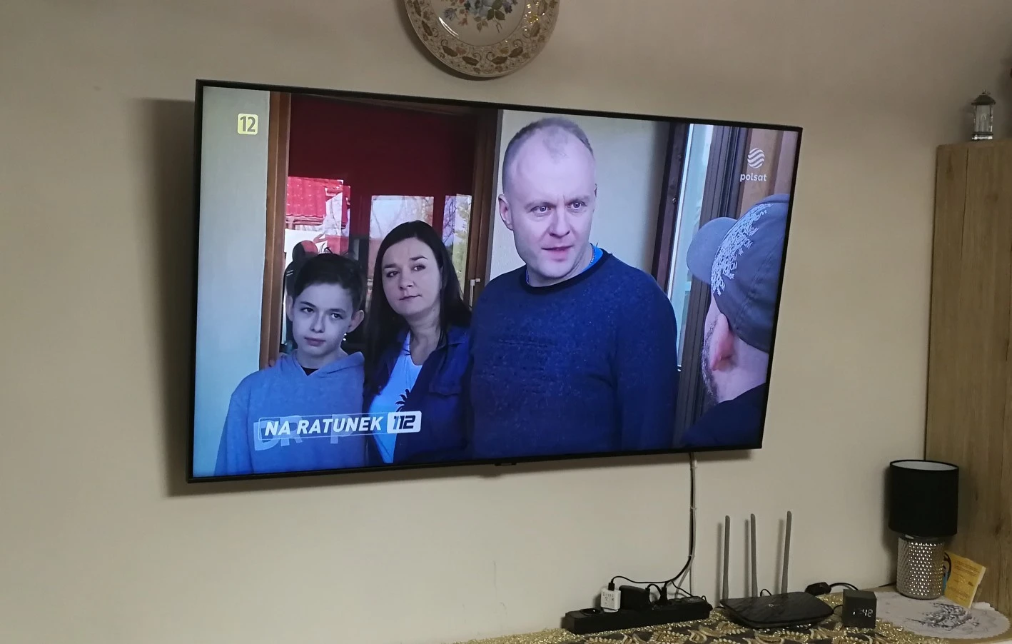 Telewizor zamontowany na ścianie z podłączonym sprzętem RTV